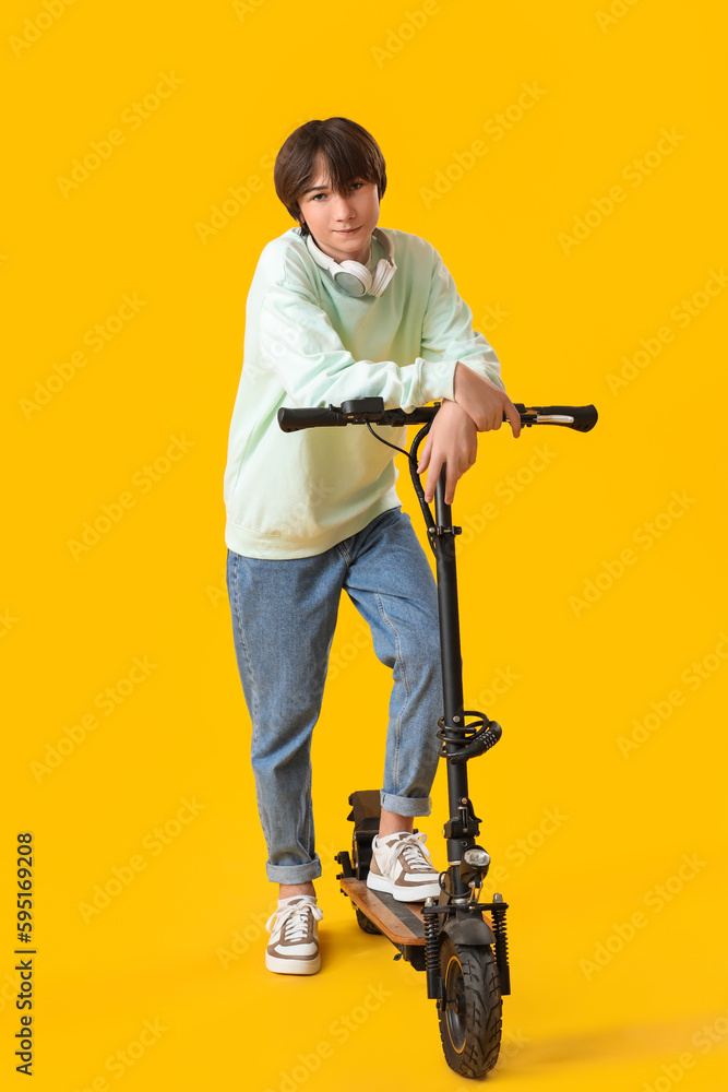 Teenage boy with electric bike on yellow background