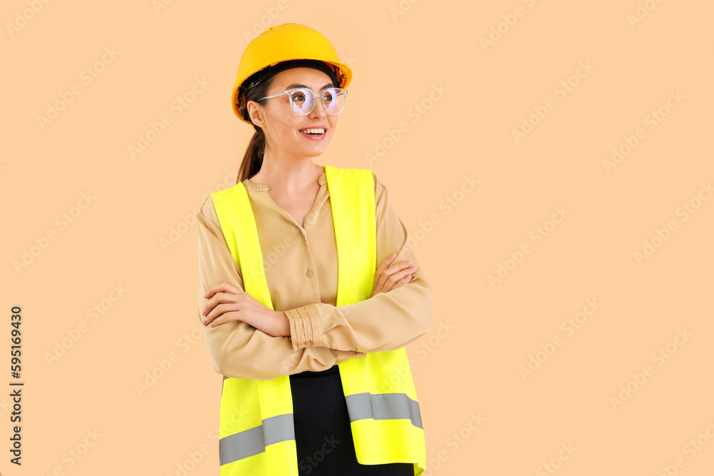 Female worker in vest and hardhat on beige background