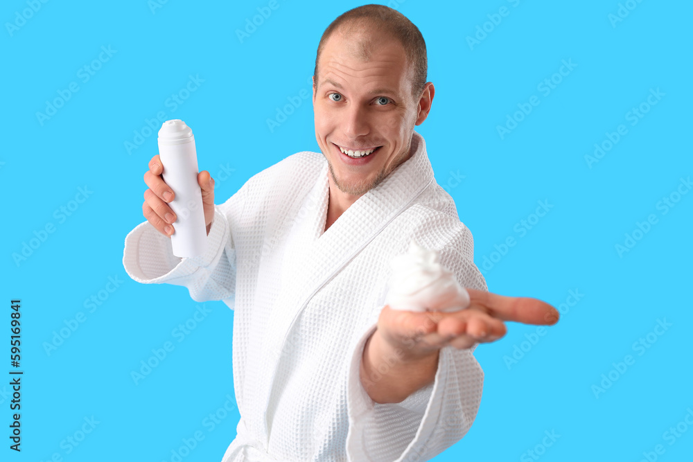 Young man with shaving foam on light blue background