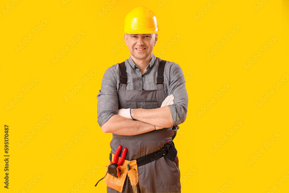 Mature carpenter in hardhat on yellow background