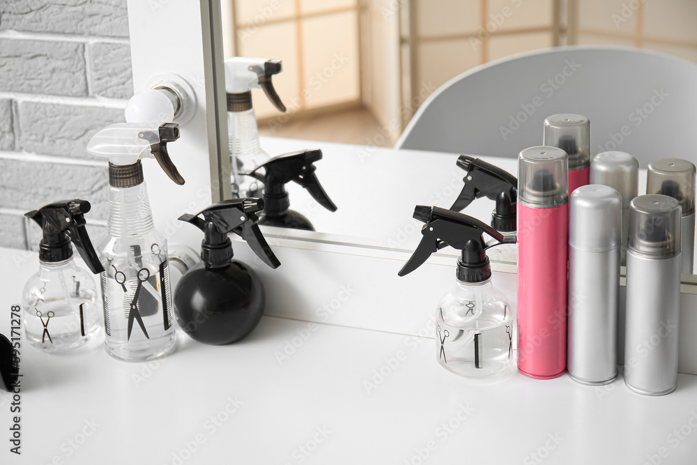 Different hair sprays and accessories on table in beauty salon