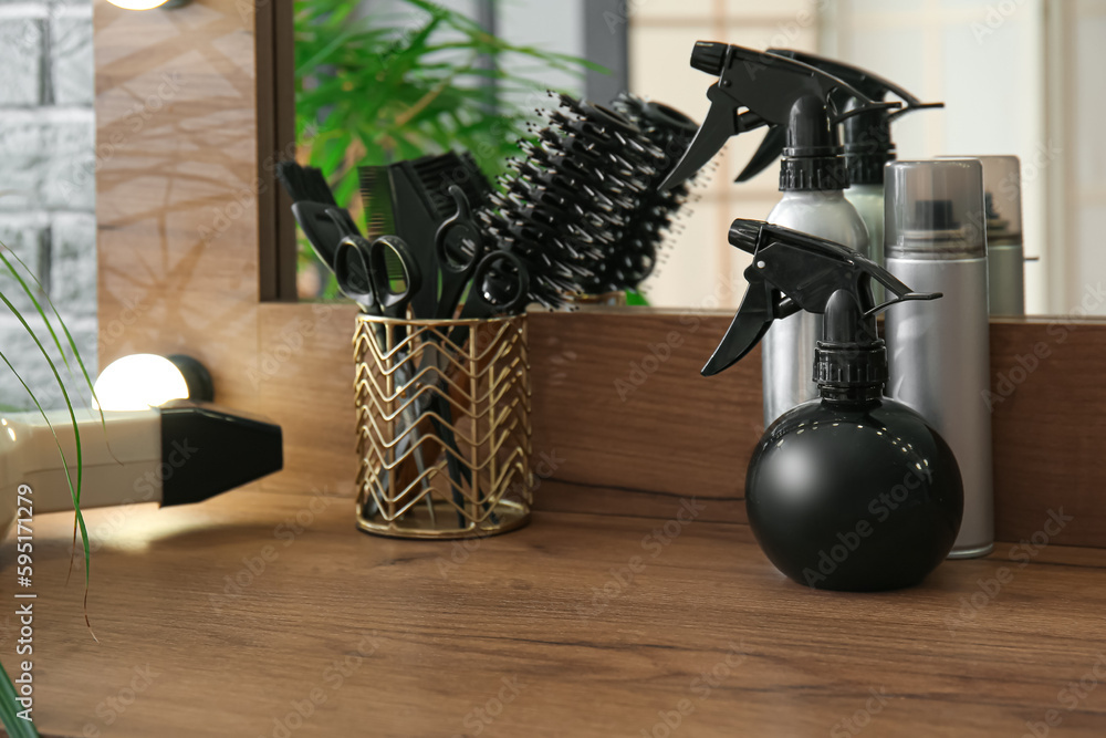 Different hair sprays and accessories on table in beauty salon