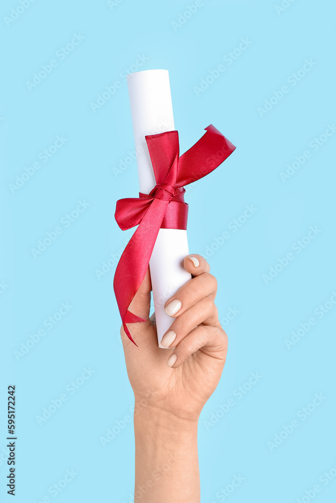 Woman holding diploma with ribbon on blue background