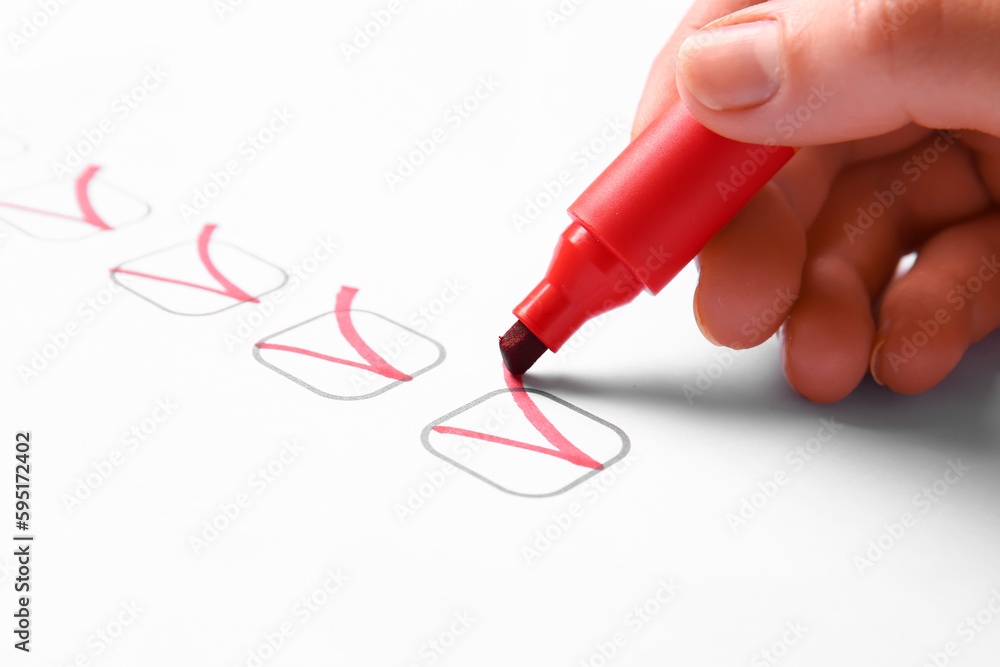 Woman marking on checklist box with red marker, closeup