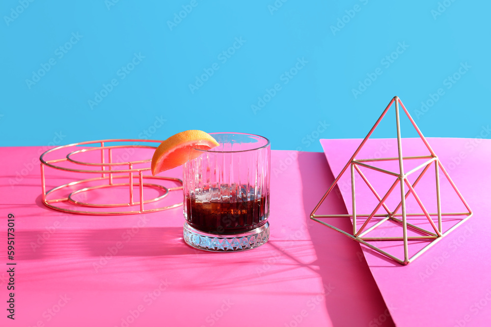 Glass of rum with grapefruit slice and decorative figures on colorful background