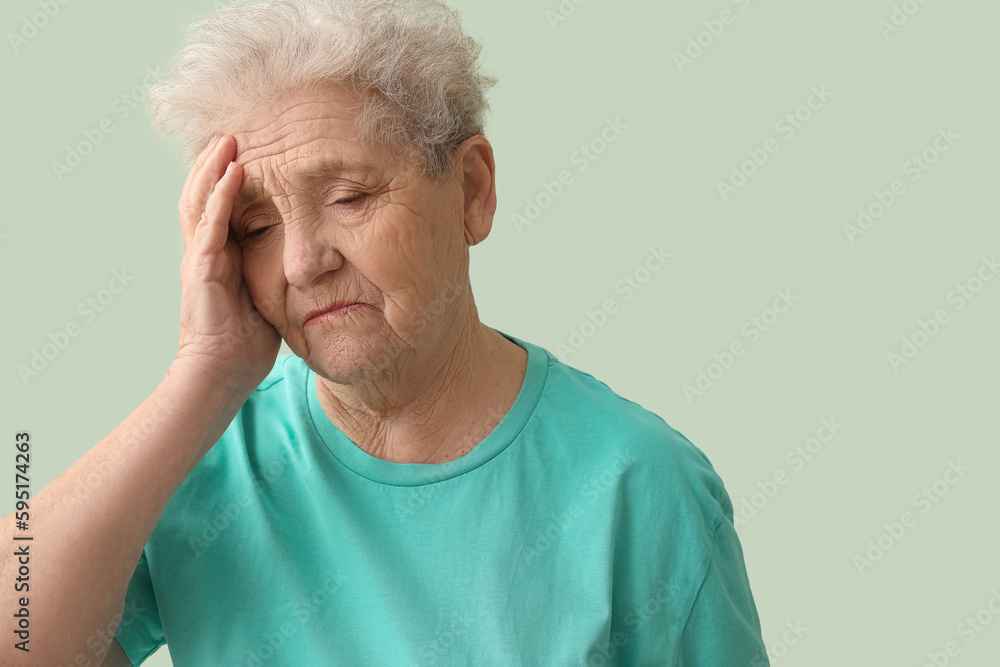 Upset senior woman on green background, closeup