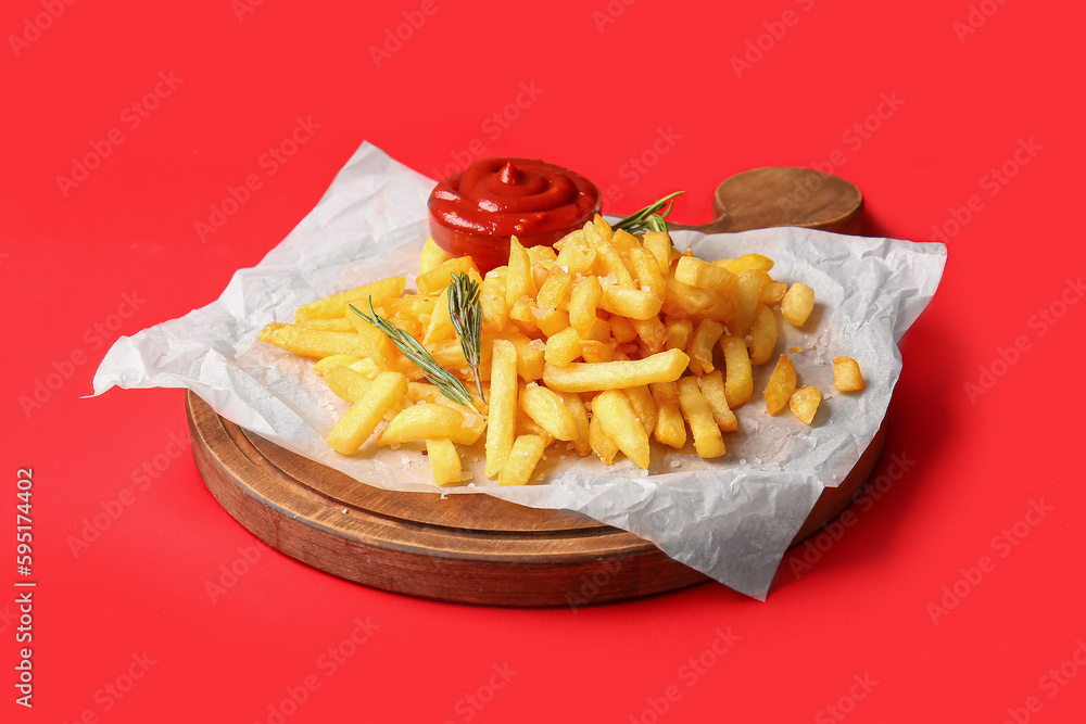 Wooden board with tasty french fries and ketchup on red background