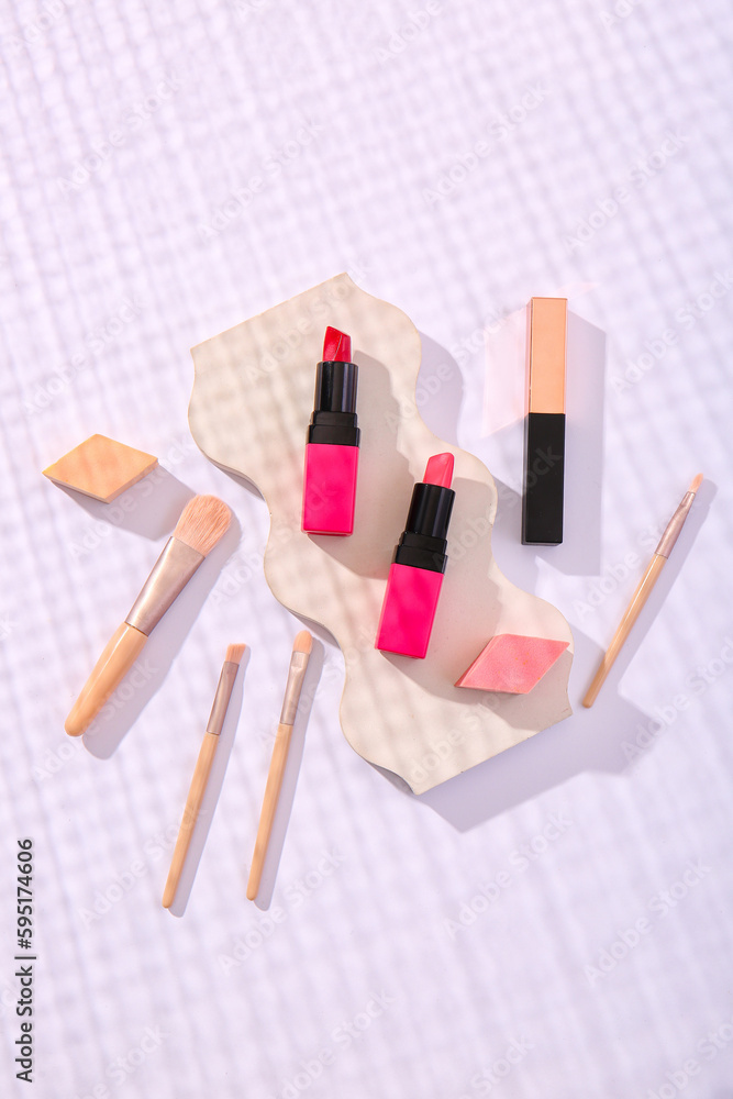 Composition with cosmetic products and makeup brushes on light background