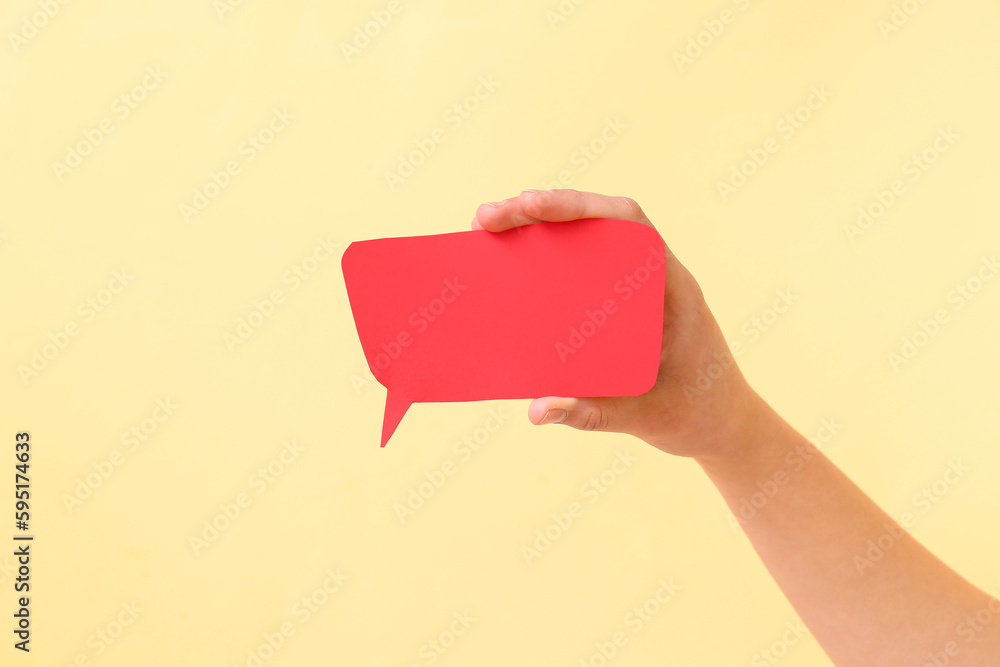 Woman holding blank speech bubble on beige background