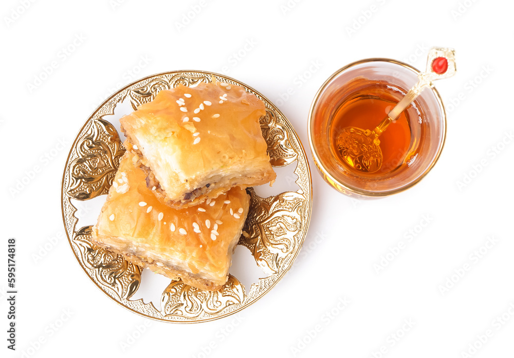 Plate with tasty baklava and glass of Turkish tea on white background