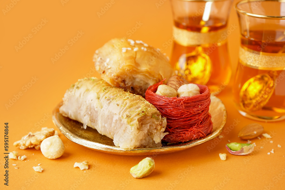 Plate with tasty baklava on orange background, closeup