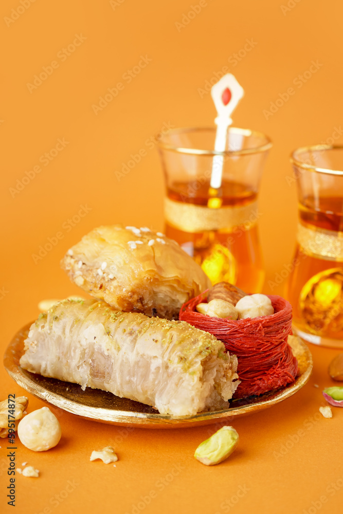 Plate with tasty baklava on orange background