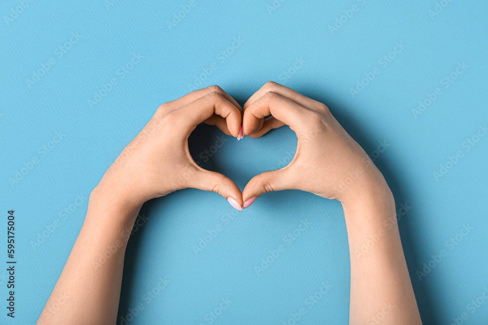 Woman making heart with her hands on blue background