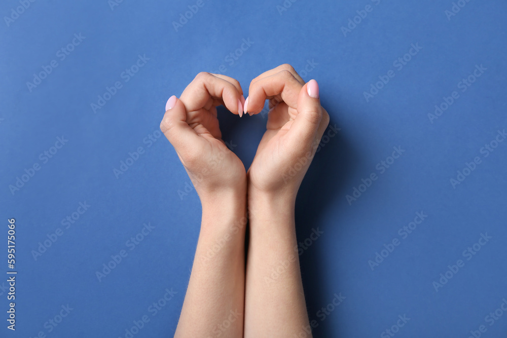 Woman making heart with her hands on blue background