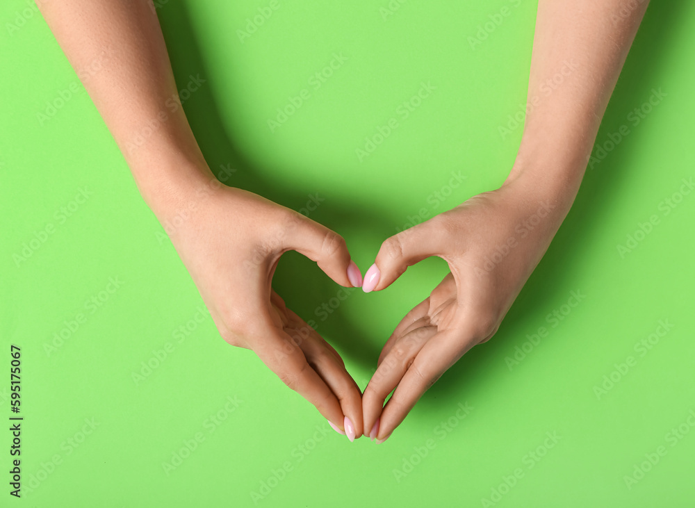 Woman making heart with her hands on green background