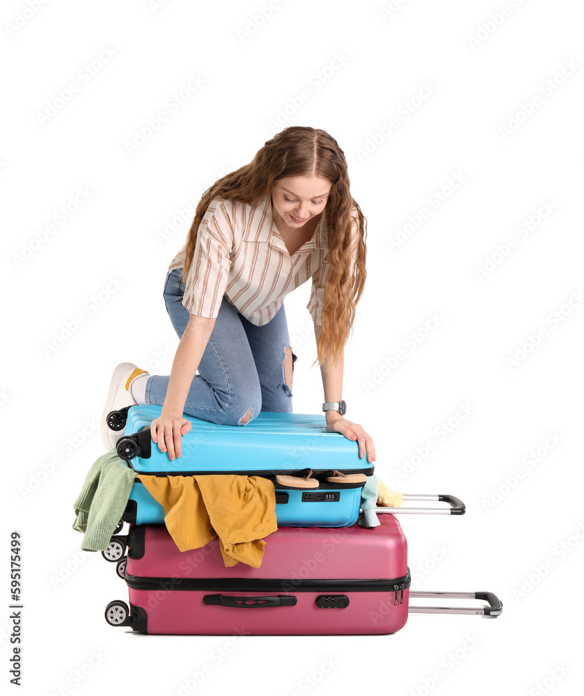 Young woman trying to close suitcase with a lot of things on white background