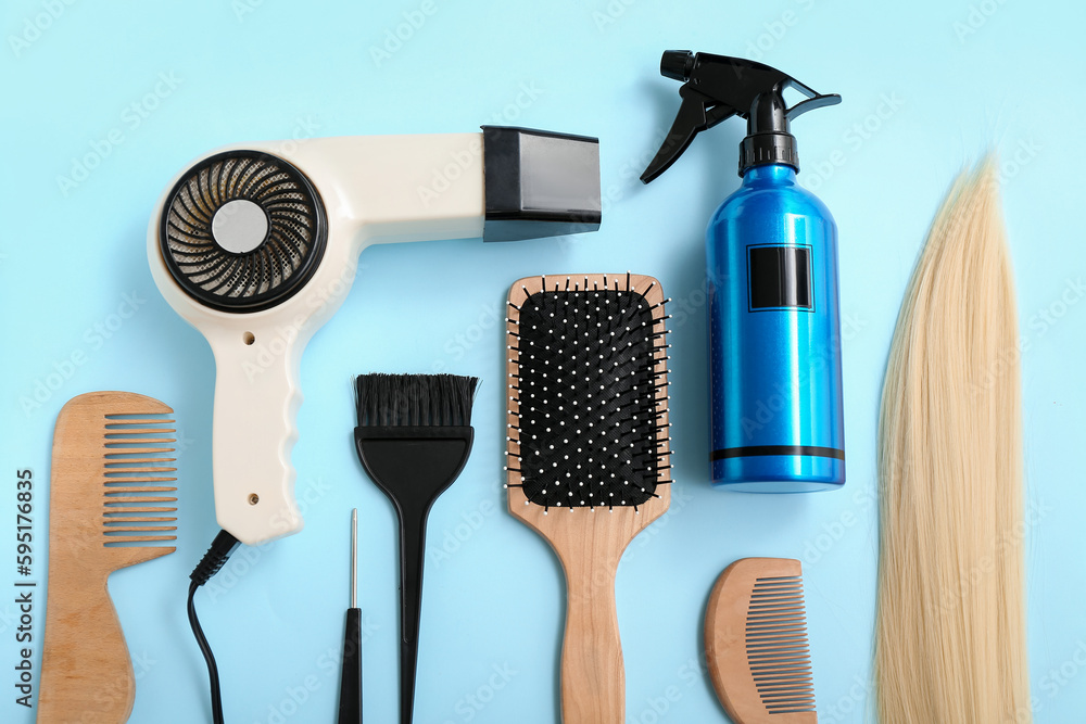 Hair strand with brushes, dryer and spray bottle on blue background