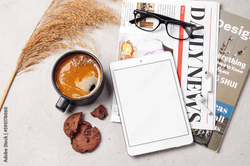 Cup of coffee with cookie, tablet computer and newspaper on white background