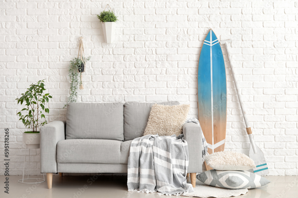 Interior of living room with surfboard, paddle and sofa