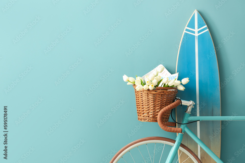 Bicycle with flowers and surfboard near blue wall