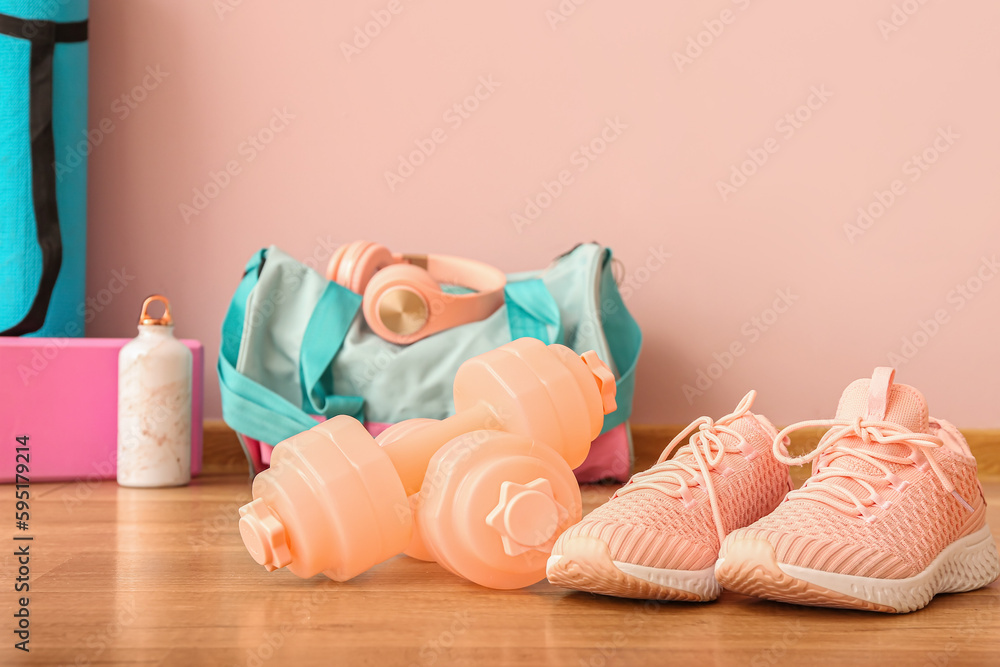 Dumbbells with sneakers on floor in gym, closeup