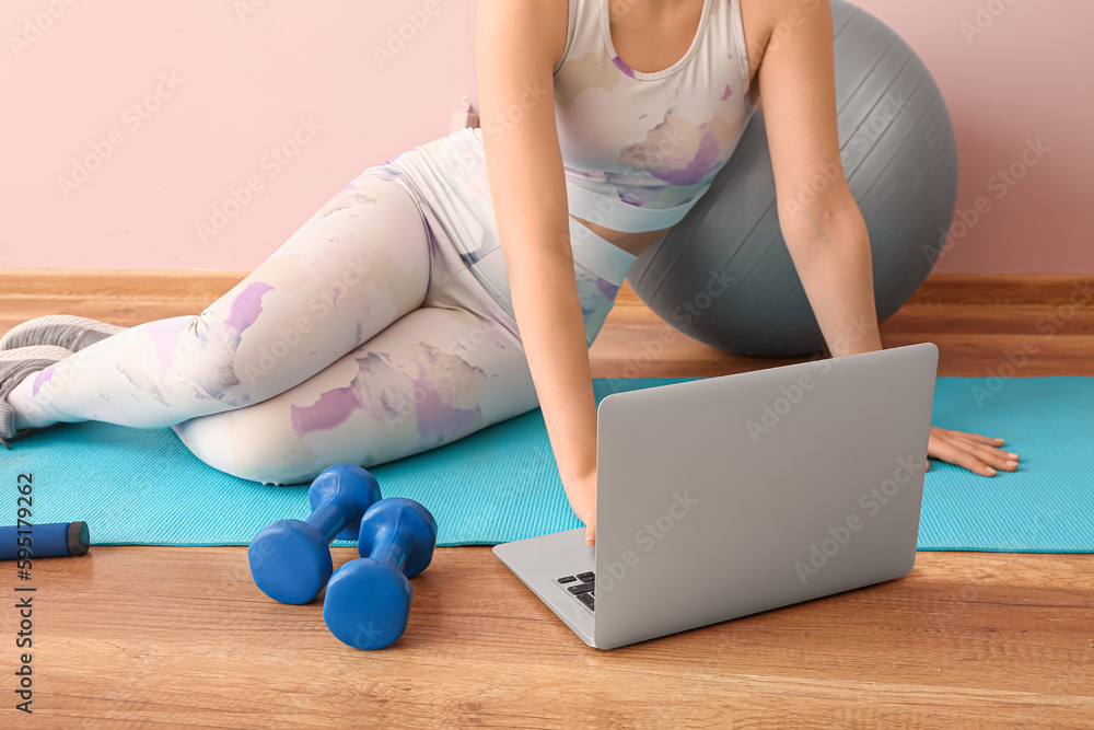 Woman with sports equipment using laptop in gym, closeup