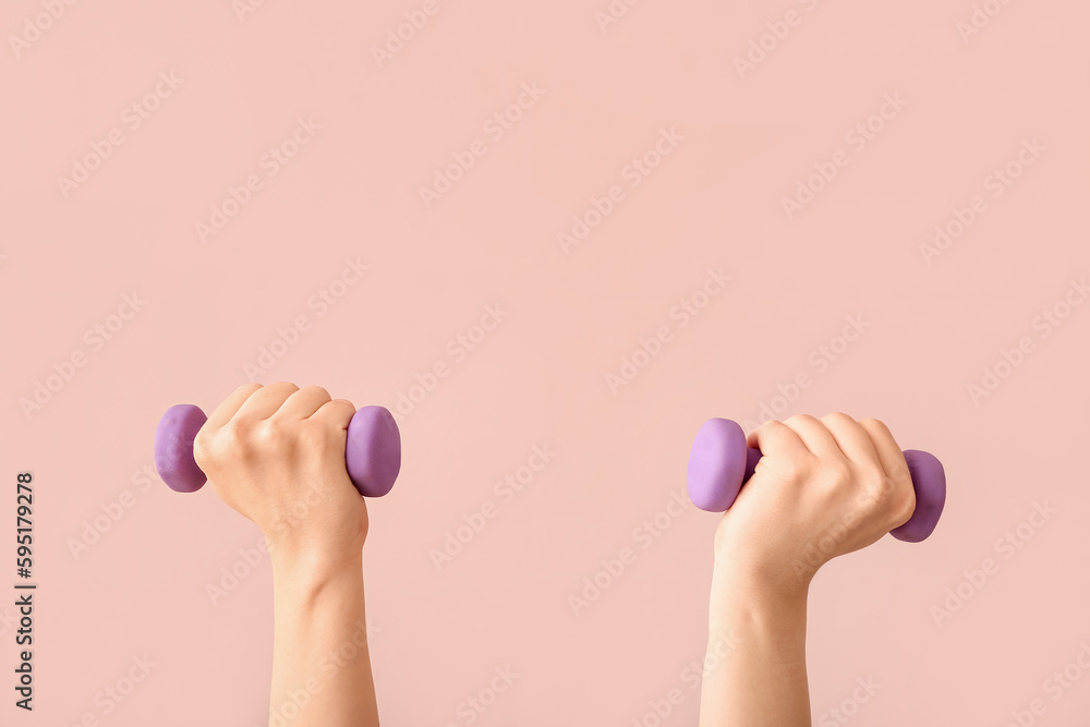 Woman with dumbbells on pink background