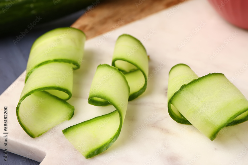 Board with slices of fresh cucumber on table, closeup