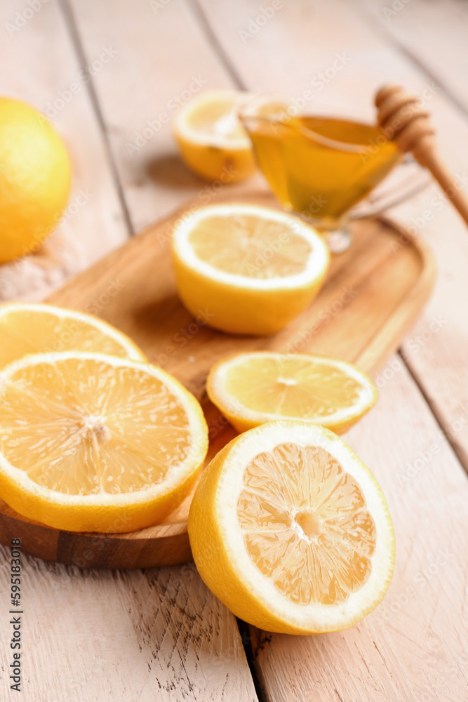 Board with fresh lemons and honey on white wooden background