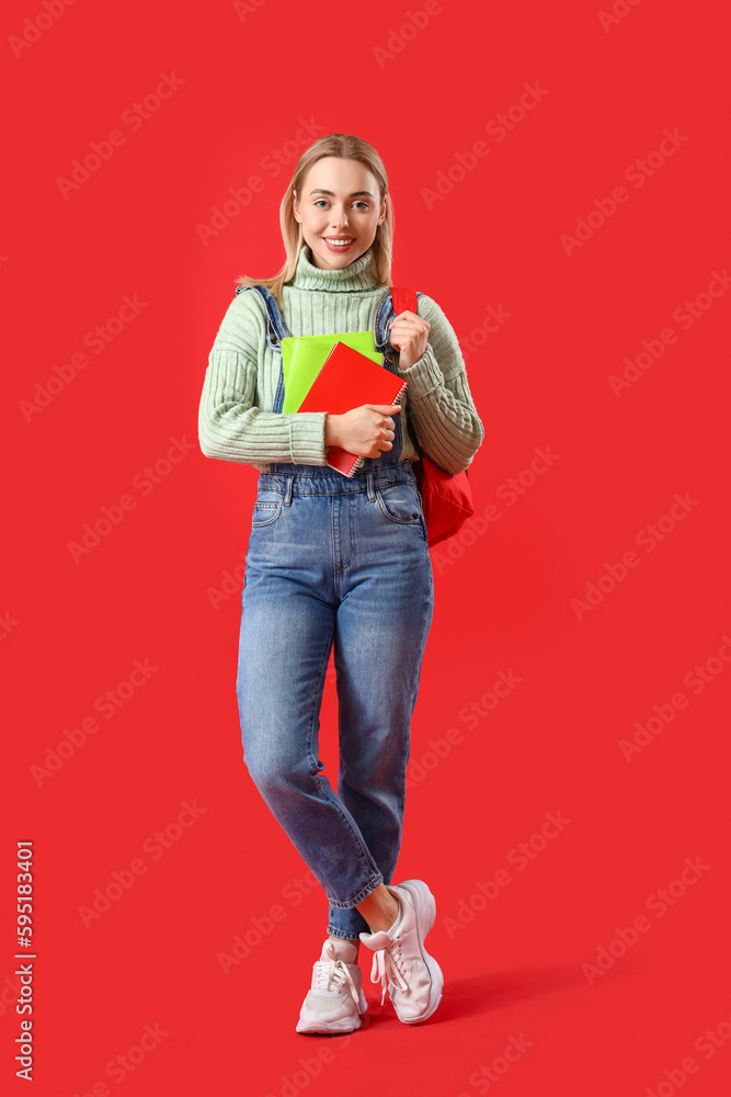 Female student with notebooks on red background