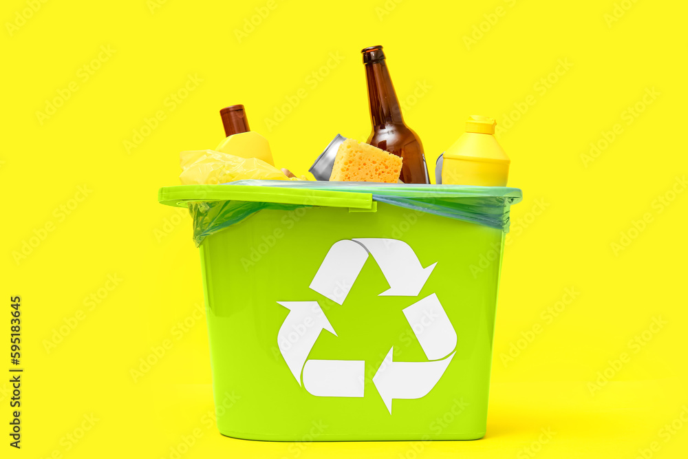 Trash bin with different garbage on yellow background