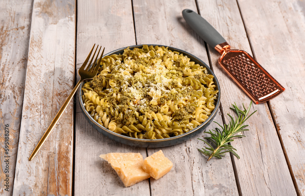 Plate of tasty Italian pasta with Parmesan cheese on light wooden background