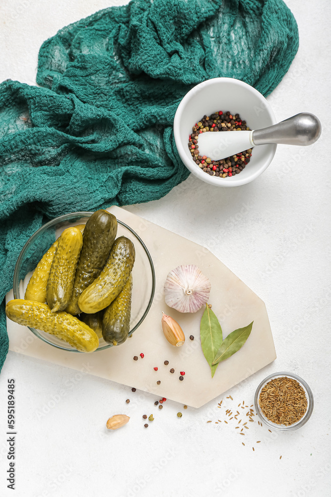 Bowl with tasty fermented cucumbers on light background