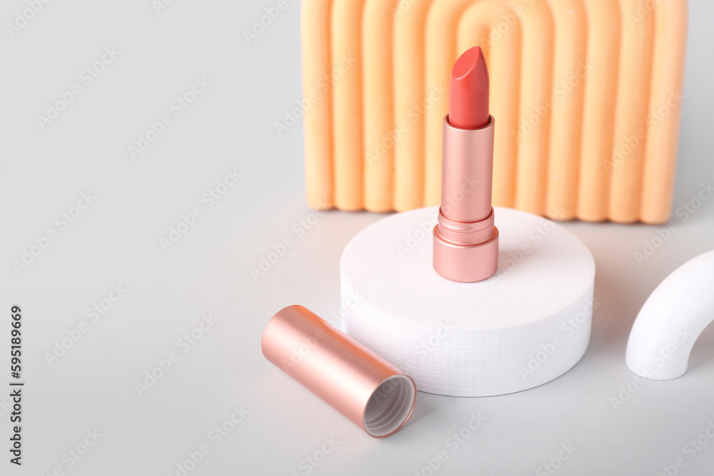 Decorative plaster podiums and lipstick on grey background