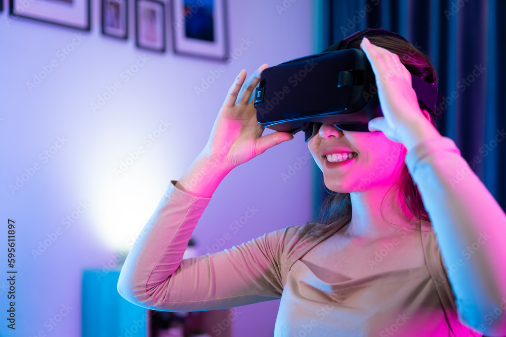 Asian modern female gamer having serious fun playing games from VR console in RGB gaming room.