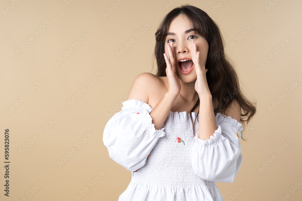 Young Asian woman doing a shocked surprise gesture shouting with hands cupped around mouth isolated 