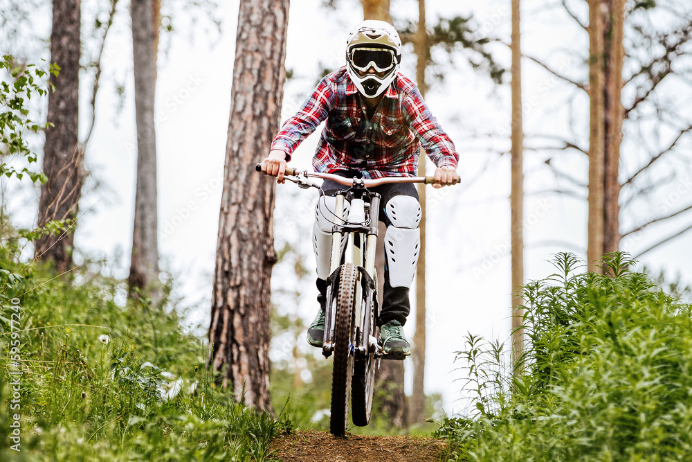 front view racer athlete riding downhill race in mountain bike, on him protection knee and shin guar