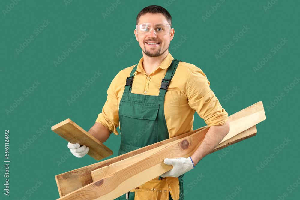 Male carpenter with wooden planks on green background