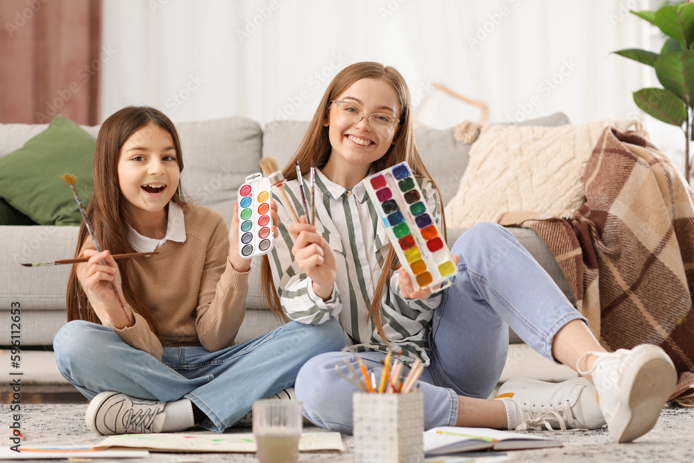 Little girl and her drawing teacher with paint brushes at home