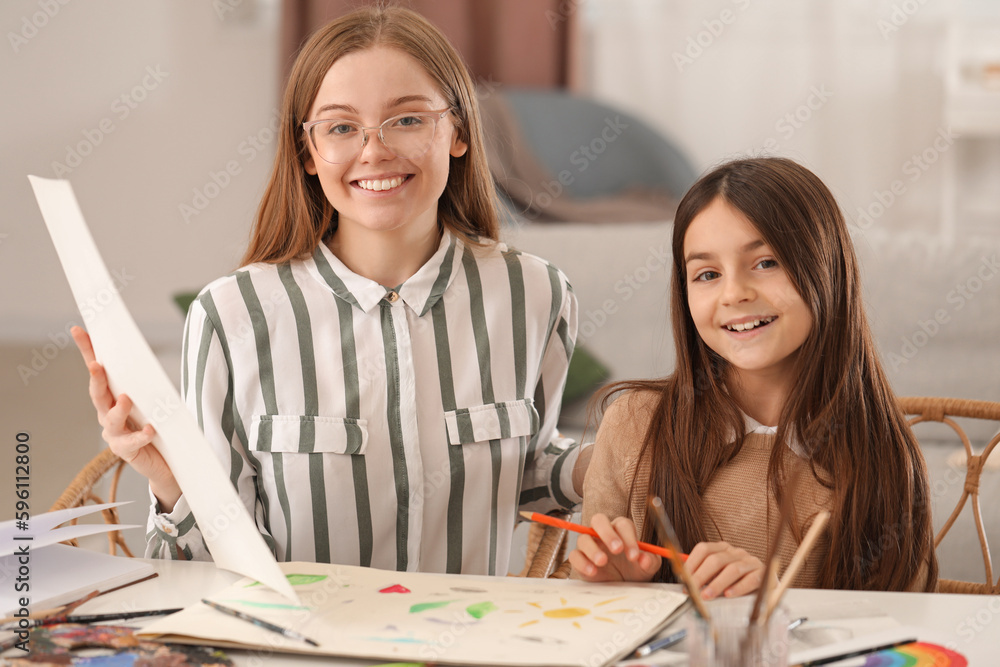 Drawing teacher giving private art lesson to little girl at home