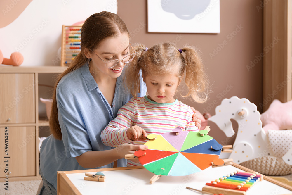 Mother and her little daughter playing matching game with clothespins at home