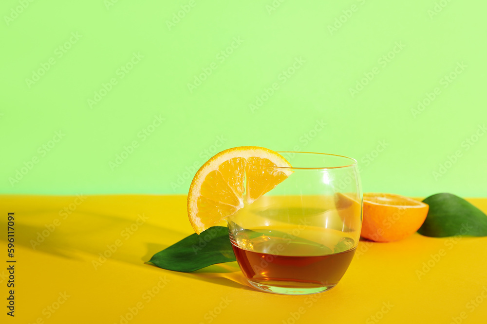 Glass of rum with slice of lemon and orange on colorful background