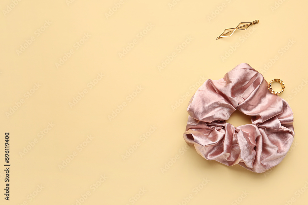 Silk scrunchy, ring and hairpin on color background