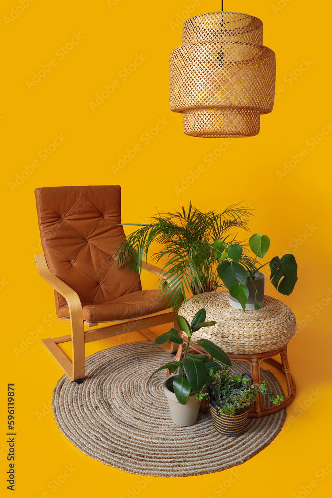 Cozy brown armchair, pouf, houseplants and lamp on orange background