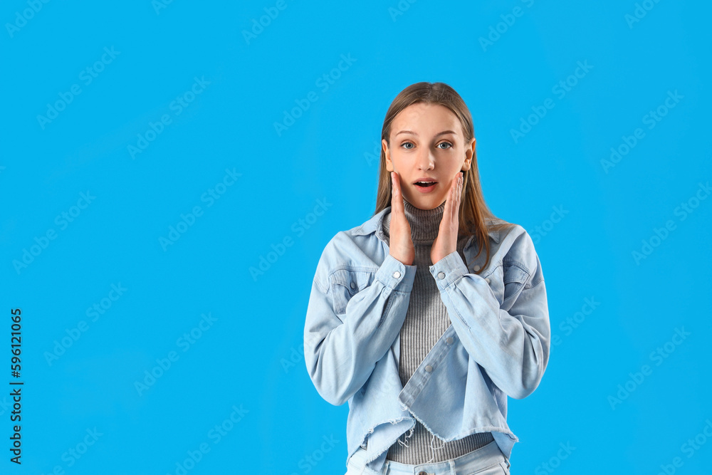 Shocked female student on blue background