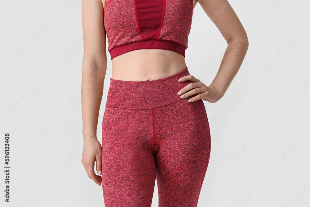 Sporty young woman in leggings on white background