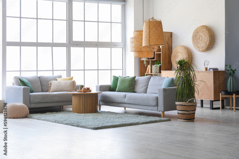 Interior of bright living room with cozy grey sofas and coffee table on soft carpet