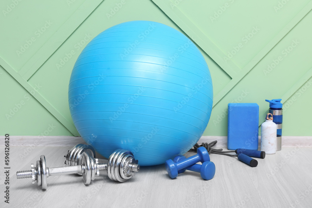 Sports equipment with dumbbells near green wall in gym