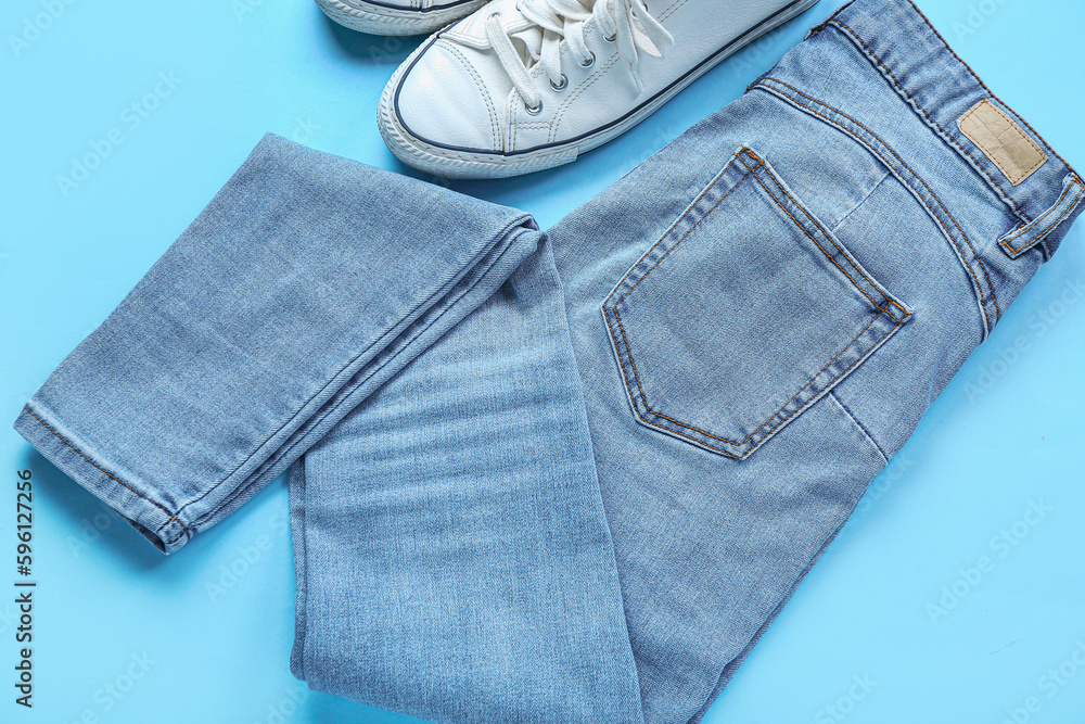 Stylish jeans with sneakers on blue background