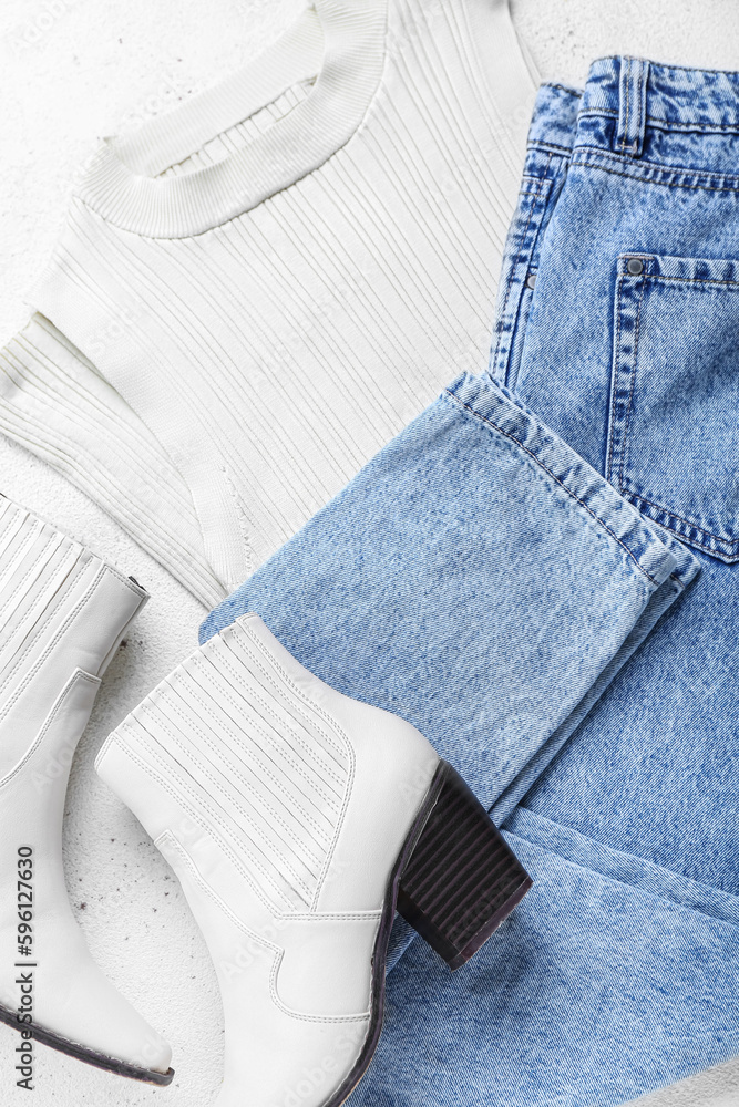 Stylish jeans with vest and boots on white background, closeup